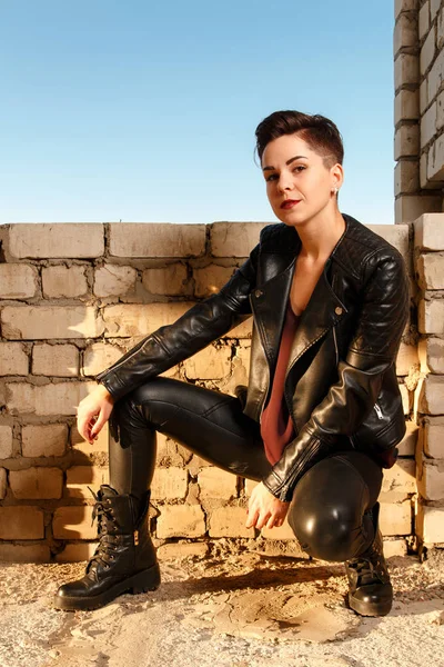 Young girl dressed in leather clothes, posing in abandoned buil