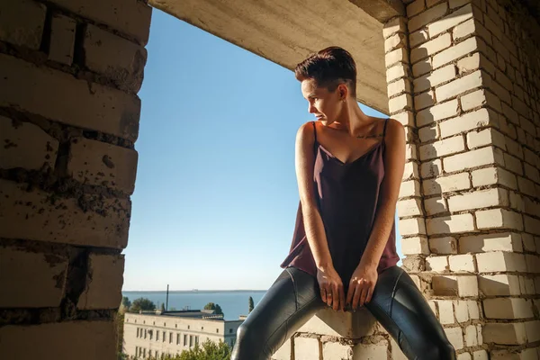 Chica joven vestida con ropa de cuero, posando en el bullicio abandonado —  Fotos de Stock