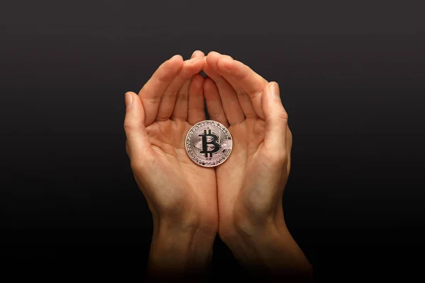 Manos femeninas sosteniendo Bitcoin plata sobre fondo negro —  Fotos de Stock
