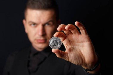Adam bitcoins koyu arka plan üzerinde tutuyor