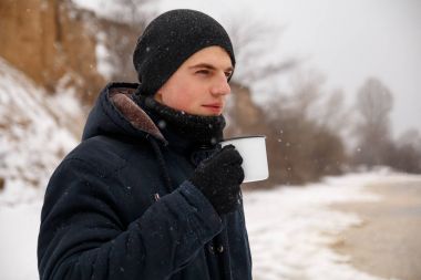 İçme çay veya kahve kış ormanda genç adam.