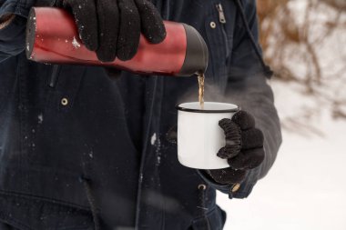 Bir adam bir termos çay bir fincan içine yağıyor