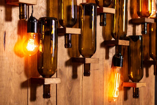 Mur en bois avec bouteilles de vin vides et lampes à incandescence . — Photo