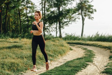 Genç kız gün batımında ormanda koşar.