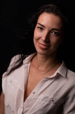 Genç esmer kızın portresi karanlık stüdyoda bir sandalyede oturuyor..