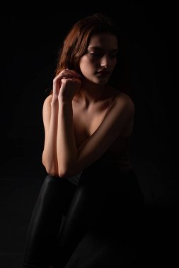 Karanlık bir stüdyoda genç bir kıvırcık kızın portresi.