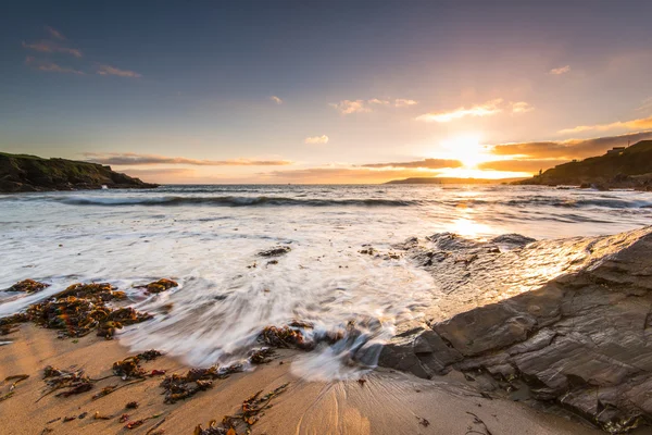 Fantastisk solnedgång på steniga och sandiga strand — Stockfoto