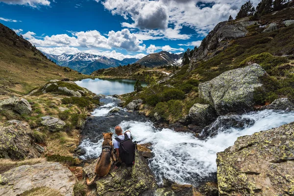 Hombre activo sentado en la roca con el perro durante el trekking — Foto de Stock