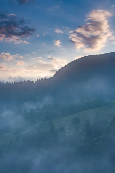 Evening sun rays breaking through the clouds and fog in mountain — Stock Photo, Image