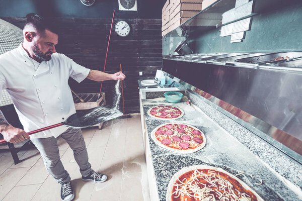 Bearded tattoed pizzaiolo chef at local pizzeria business.