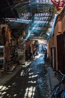 Yerli halk ve Marakeş'te dar sokakta yürüyen turist