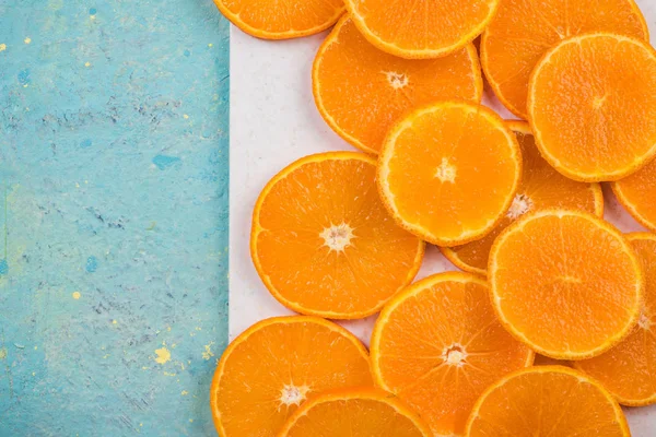 大理石板和蓝桌上的橙色切片 — 图库照片