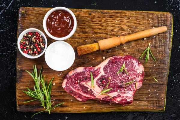 Het stuk vlees met kruiden en specerijen op houten bord — Stockfoto