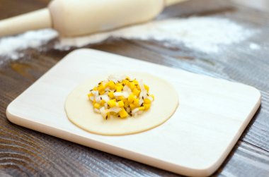 Mısır ve soğan, bir ahşap tahta, oklava ve un ile çiğ hamur çemberi