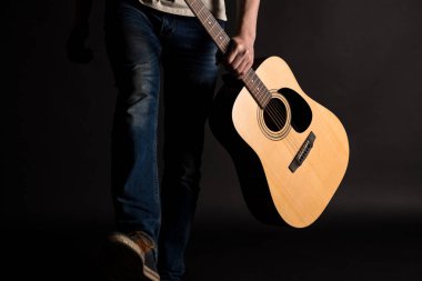 Sol elinde siyah bir yalıtılmış zemin üzerine bir akustik gitar gitarist geliyor