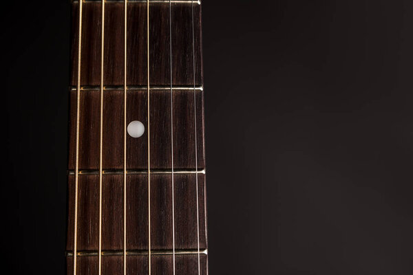 Part of the neck, wooden acoustic guitar, on the left side of the frame