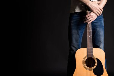 Gitarist izole bir siyah arka plan üzerine bir akustik gitar ile iki el ele tutuşarak