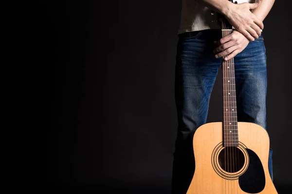 Chitarrista che tiene due mani con una chitarra acustica su uno sfondo nero isolato — Foto Stock