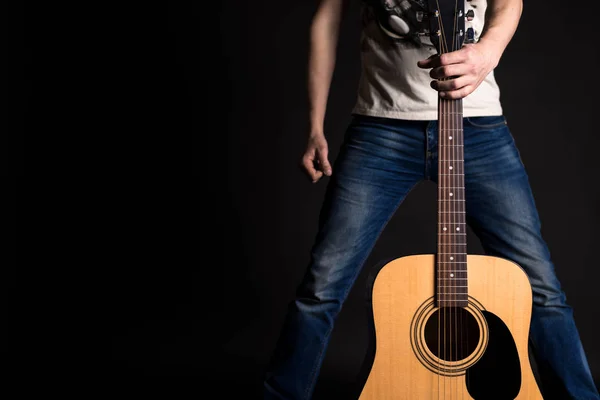 Il chitarrista tiene la mano sinistra con una chitarra acustica davanti a sé, su uno sfondo nero isolato — Foto Stock