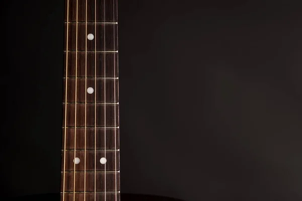 Part of the neck, wooden acoustic guitar, on the left side of the frame, on a black isolated background — Stock Photo, Image