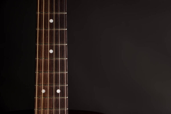 Part of the neck, wooden acoustic guitar, on the left side of the frame