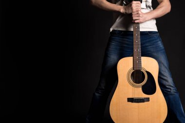 Gitarist izole bir siyah arka plan üzerine bir akustik gitar ile iki el ele tutuşarak
