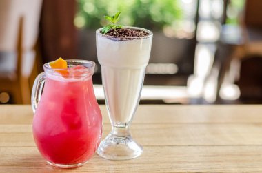 Bir sürahi limon ve beyaz çikolata ve nane ahşap bir masa, yan görünümü ile bir bardak kokteyl kırmızı meyve suyu