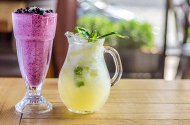 Çilek ve bir sürahi suyu ve otlar, ahşap bir masa üzerinde tonlama sarı kokteyl serinletici pembe. Yan görünüm