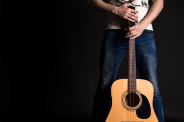 Gitarist izole bir siyah arka plan üzerine bir akustik gitar ile iki el ele tutuşarak