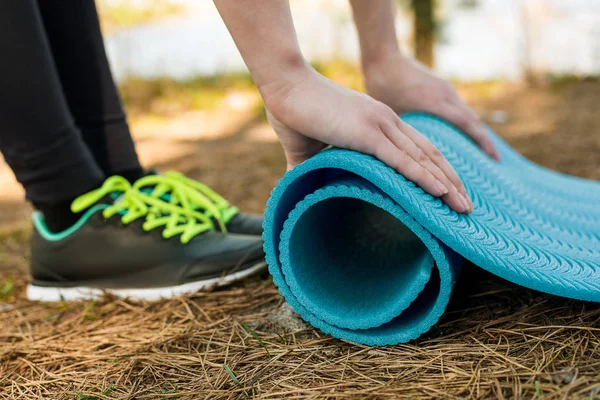 Девочка в спортивной обуви прядет синий каремат на природе, для йоги, — стоковое фото
