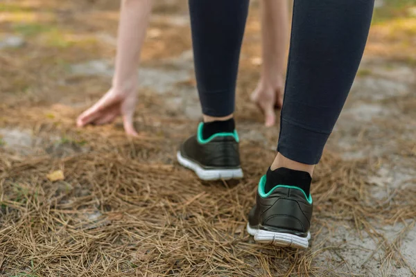 Girl in sports pants and shoes, stands at the start before runni