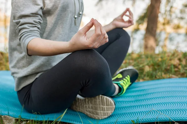 Chica en un traje deportivo, al aire libre, meditando, sentado en una sp azul — Foto de Stock