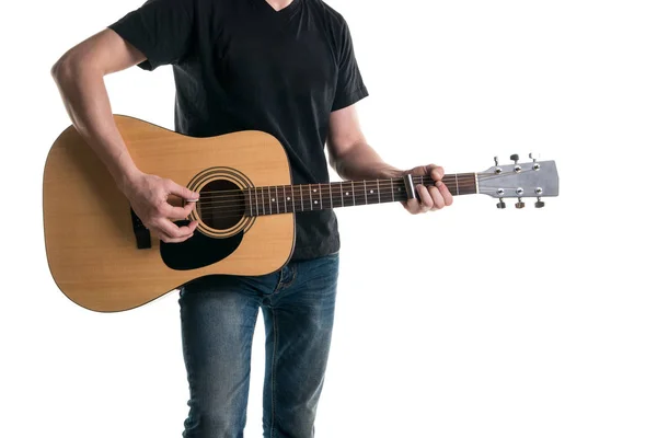 Ο κιθαρίστας με τζιν και ένα μαύρο T-shirt, παίζει μια ακουστική κιθάρα με ένα ρυθμιστικό, στην αριστερή πλευρά του πλαισίου, σε λευκό φόντο. Οριζόντιο πλαίσιο — Φωτογραφία Αρχείου