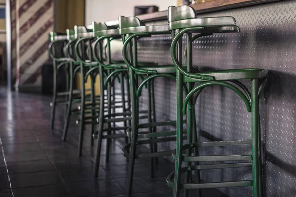 Banquetas de barra verde vintage ficam em uma fileira ao lado do balcão do bar. Quadro horizontal — Fotografia de Stock