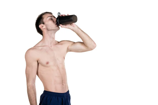 Hälsosam livsstil och fitness. Stilig kille sport en kroppsbyggnad, med en naken kropp, dricker vatten ur en flaska, isolerad på en vit bakgrund. Horisontell ram — Stockfoto
