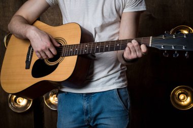 Gitar çalıyor. Akustik gitar gitarist elinde. Yatay Çerçeve