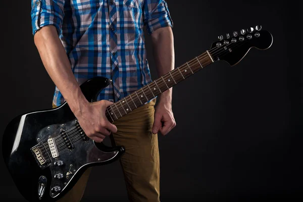 Musica e arte. Il chitarrista tiene una chitarra elettrica nella mano destra, su uno sfondo nero isolato. Suona la chitarra. Telaio orizzontale — Foto Stock