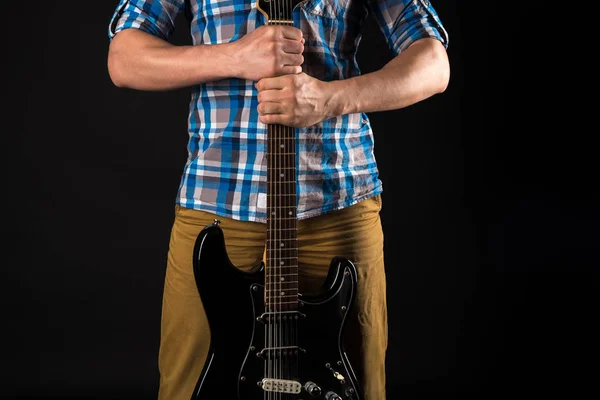 Música e arte. O guitarrista segura a guitarra elétrica com as mãos, sobre um fundo preto isolado. A tocar guitarra. Quadro horizontal — Fotografia de Stock
