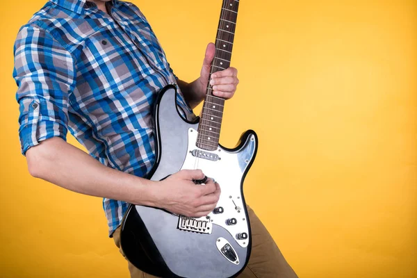 Musica e arte. Il chitarrista suona la chitarra elettrica su uno sfondo giallo isolato. Suona la chitarra. Telaio orizzontale — Foto Stock