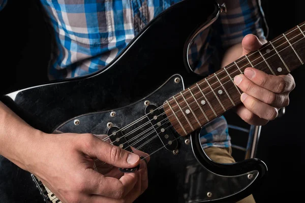 Musica e arte. Chitarra elettrica nelle mani di un chitarrista, su uno sfondo nero isolato. Suona la chitarra. Telaio orizzontale — Foto Stock