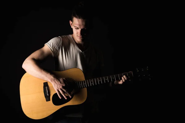 Guitarrista, música. Um jovem toca guitarra acústica num fundo preto isolado. Quadro horizontal — Fotografia de Stock