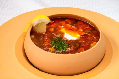 Ekşi krema, otlar ve limon, koyu sarı tabak, beyaz masa örtüsü içinde lezzetli kırmızı çorbası. Yatay Çerçeve