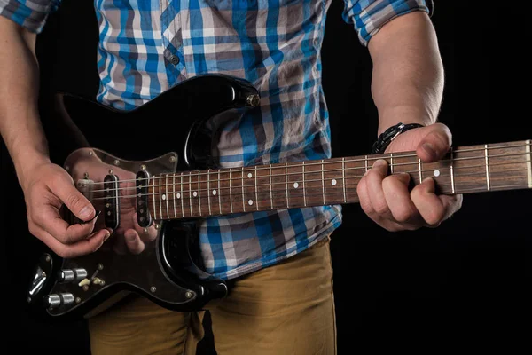 Musica e arte. Chitarra elettrica nelle mani di un chitarrista, su uno sfondo nero isolato. Suona la chitarra. Telaio orizzontale — Foto Stock