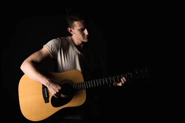 Guitarrista, música. Um jovem toca guitarra acústica num fundo preto isolado. Quadro horizontal — Fotografia de Stock