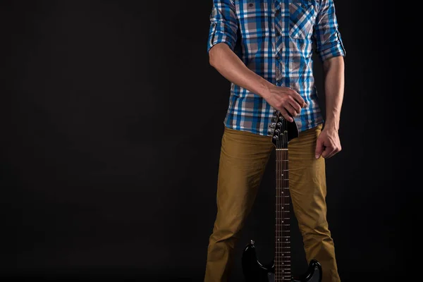 Μουσική και τέχνη. Ο κιθαρίστας κατέχει μια ηλεκτρική κιθάρα στο δεξί του χέρι, πάνω σε μαύρο φόντο απομονωμένες. Παίζοντας κιθάρα. Οριζόντιο πλαίσιο — Φωτογραφία Αρχείου