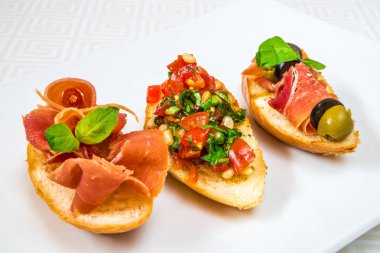 Lezzetli, ağız sulandıran farklı kanepeler et, sebzeler, otlar ve zeytin, beyaz tabakta. Yatay Çerçeve