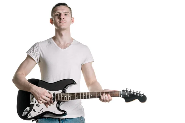 Music and creativity. A handsome young man in a T-shirt is holding an electric guitar. Horizontal frame — Stock Photo, Image