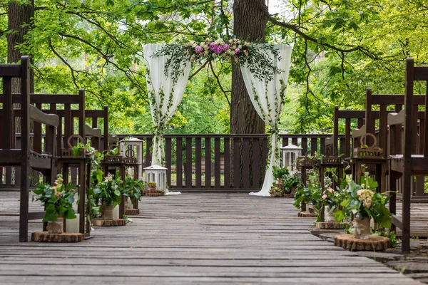 Atributos de casamento. Cerimônia de casamento. Pilares brancos de um arco de casamento, decorado com flores e bancos marrons. Quadro horizontal — Fotografia de Stock