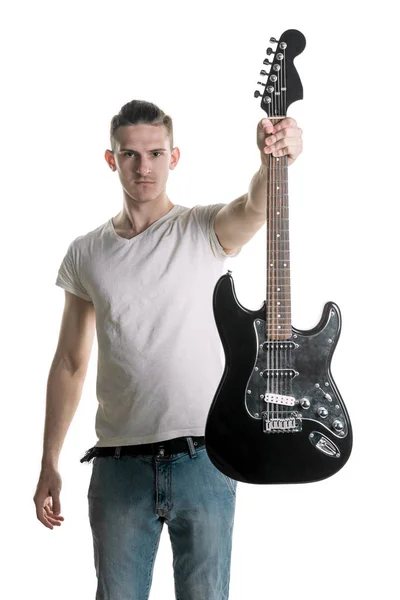 Music and creativity. A handsome young man in a T-shirt holds out an electric guitar in his hand. Play it. Horizontal frame — Stock Photo, Image