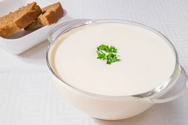 Lezzetli kahvaltı. Şeffaf bir tabak çorba beyaz, arka planda ekmek. Yatay Çerçeve — Stok fotoğraf